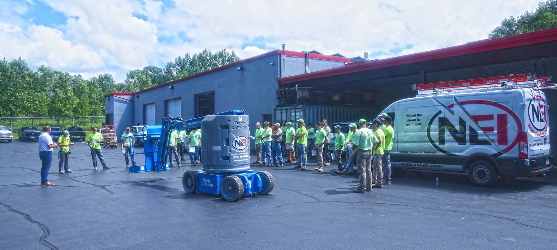 A group of NEI electricians gathered outside the shop for a lift safety training session