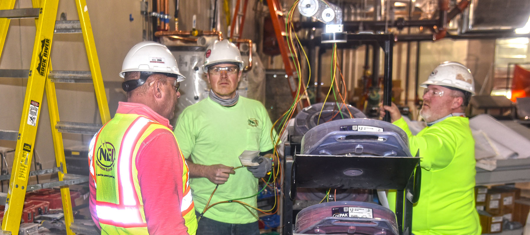 Jim Conard talking with two electricians at the Keshena Family Engagement Center job site Mianaceqtawak Keshena, WI
