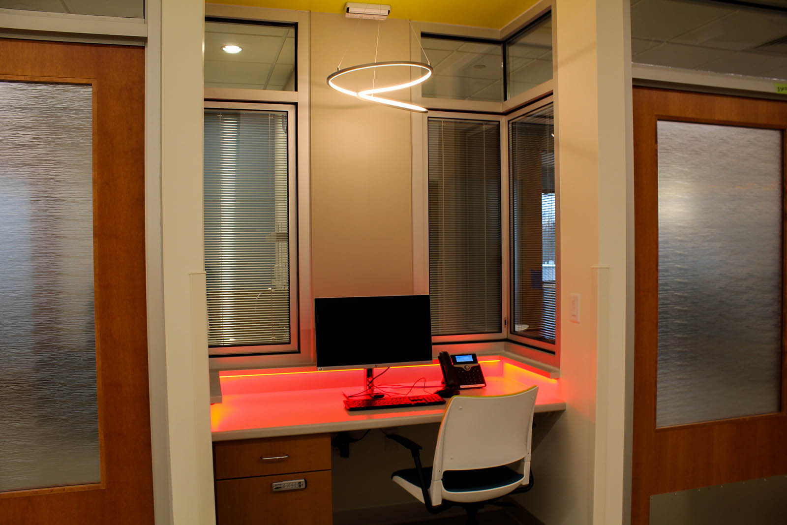 A computer station at desk with overhead LED lighting and red LED light accents surrounding the desk