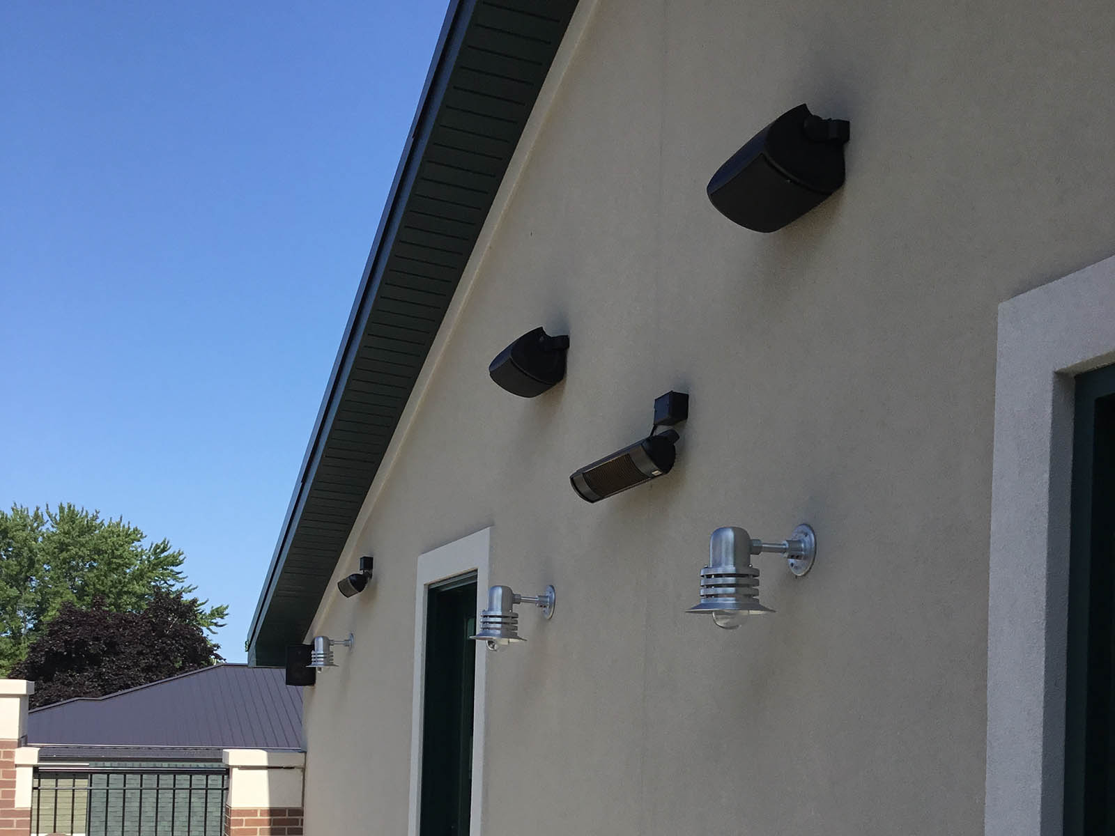 Exterior speaker system and lighting mounted on a wall to provide sound and light to upper level patio