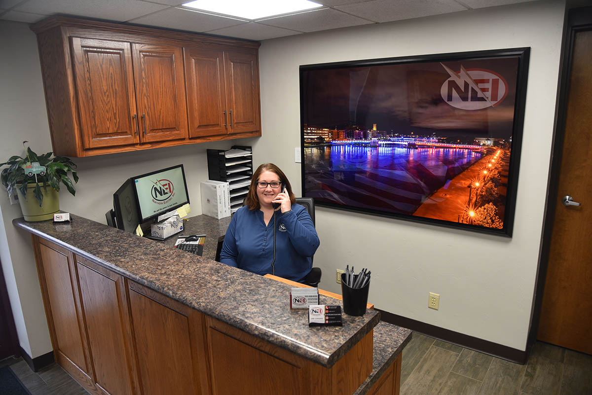 NEI office manager Amanda Rehbein at front desk answering a phone