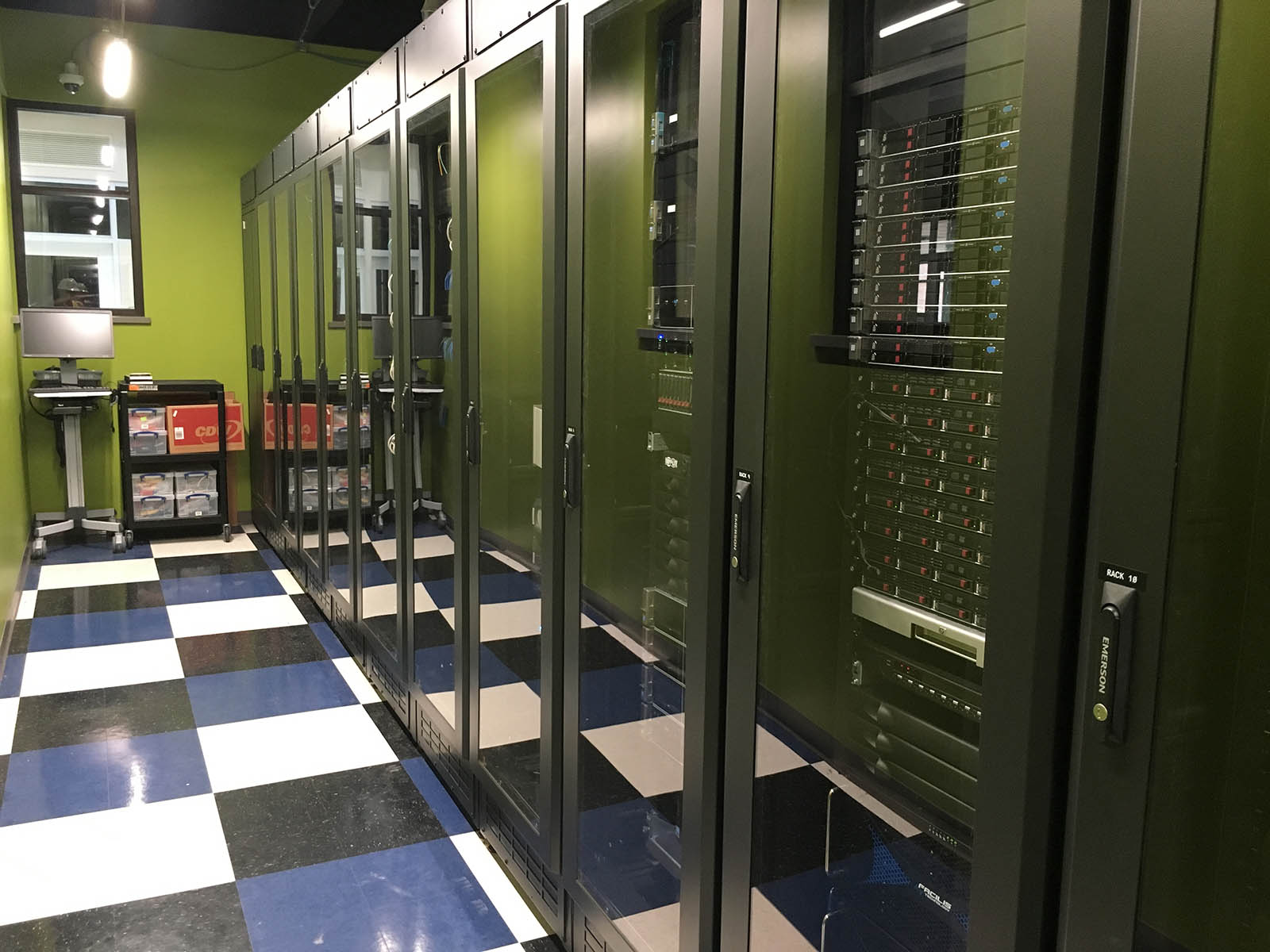 A large server and networking room filled with server enclosures with clear glass doors